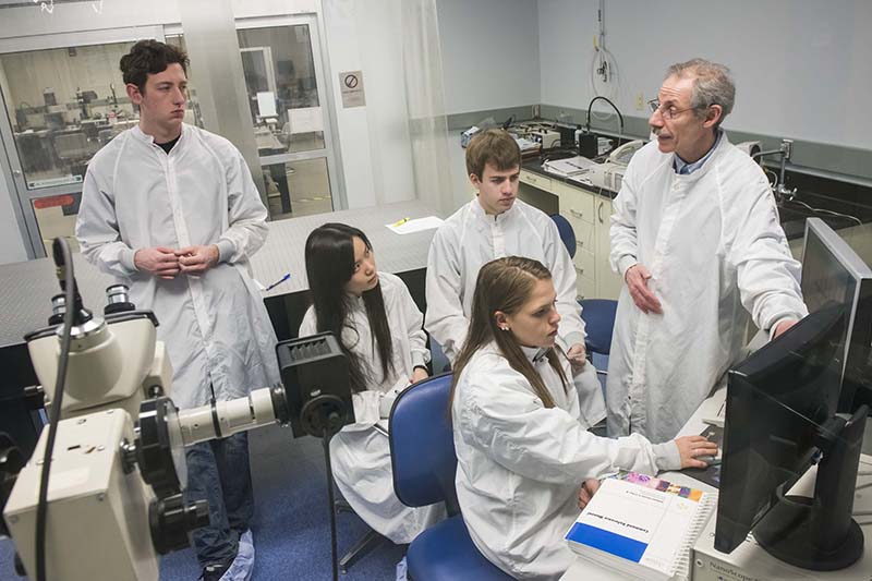 Semyon Papernov with his students in his Nanometrology class wearing white lab coats