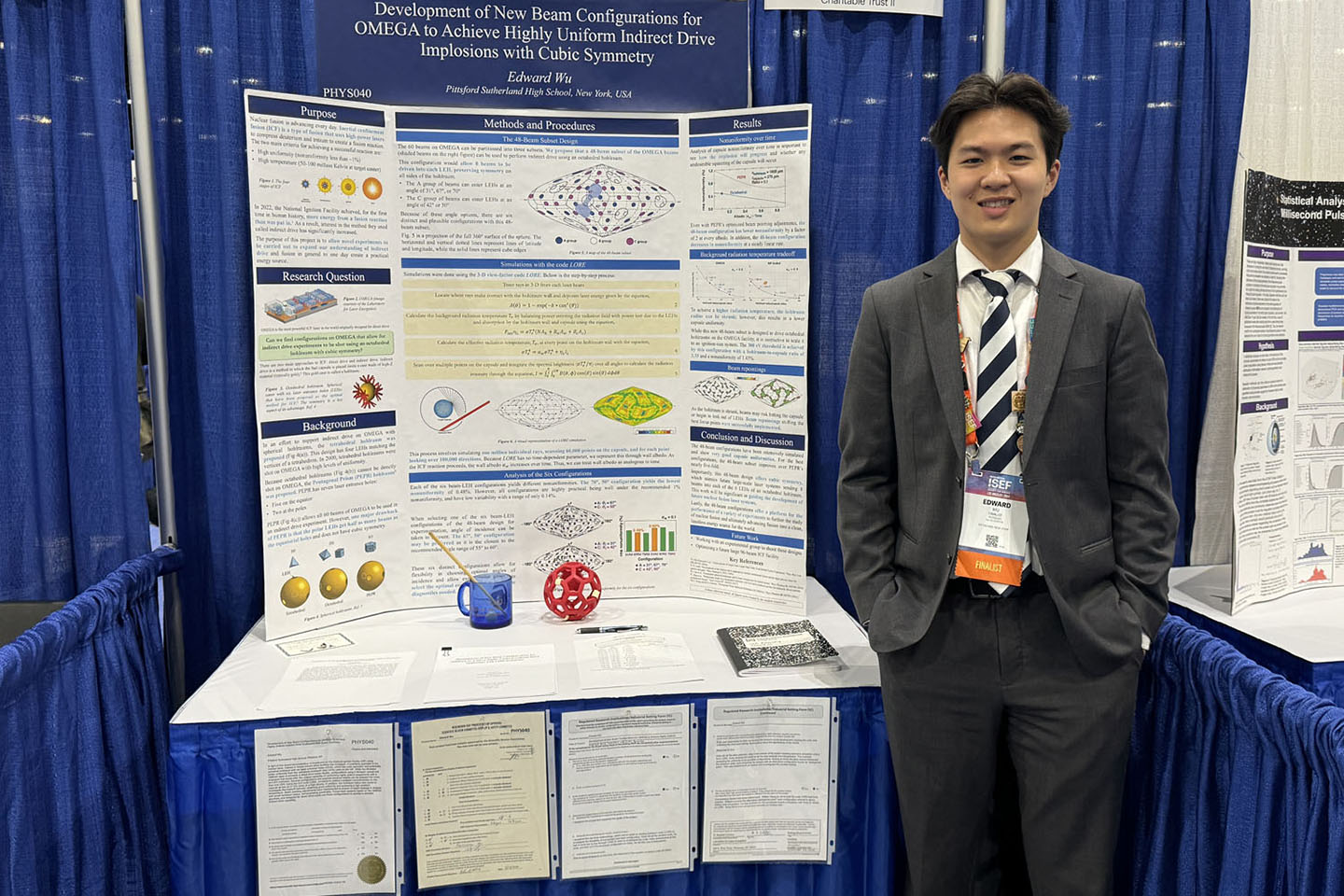 Eddy Wu standing by his scientific poster at a conference booth.