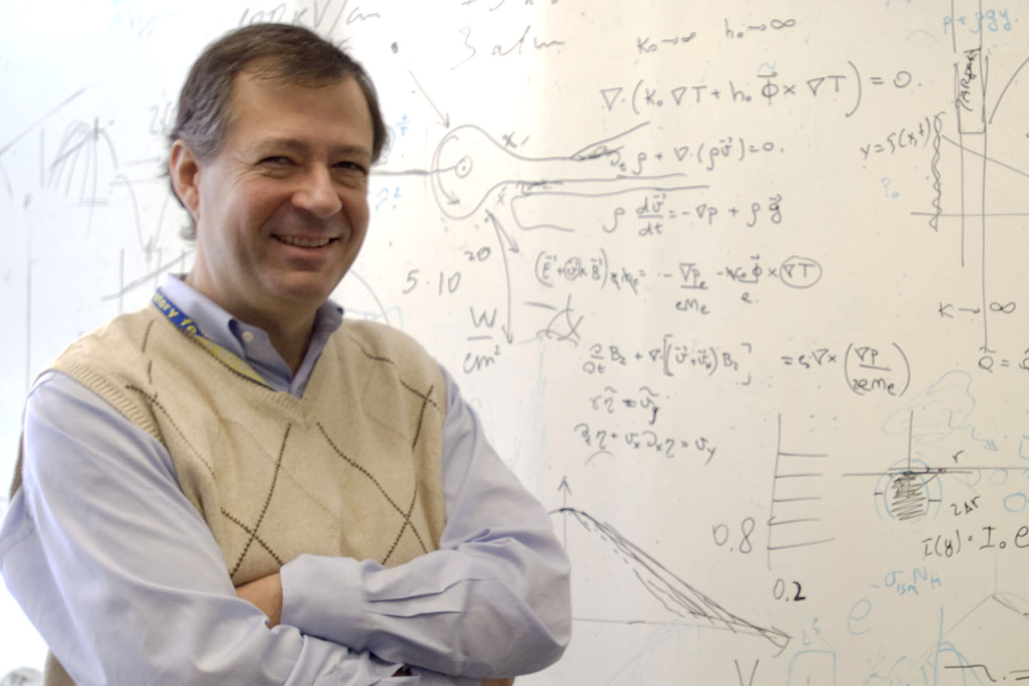 Riccardo Betti in front of a whiteboard covered in equations.