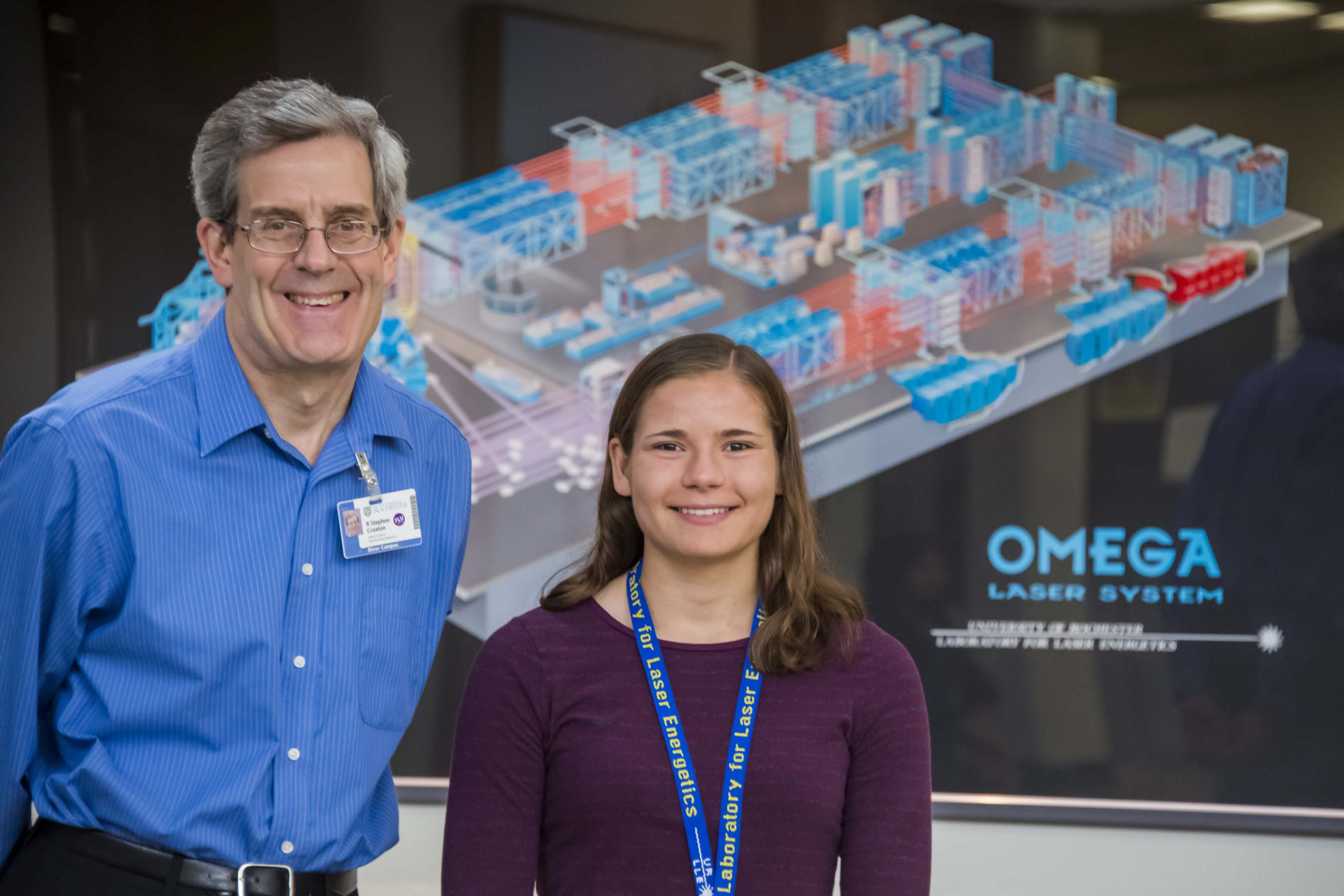 Steve Craxton and Lindsay Browning posing in front of an OMEGA Laser System poster