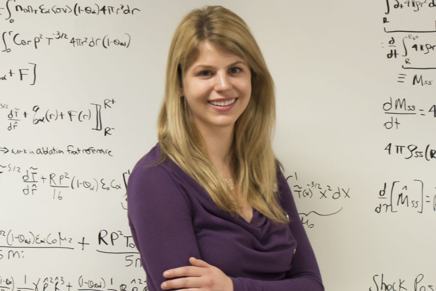 Photo of Alison Christopherson posing with equations on whiteboard in background.