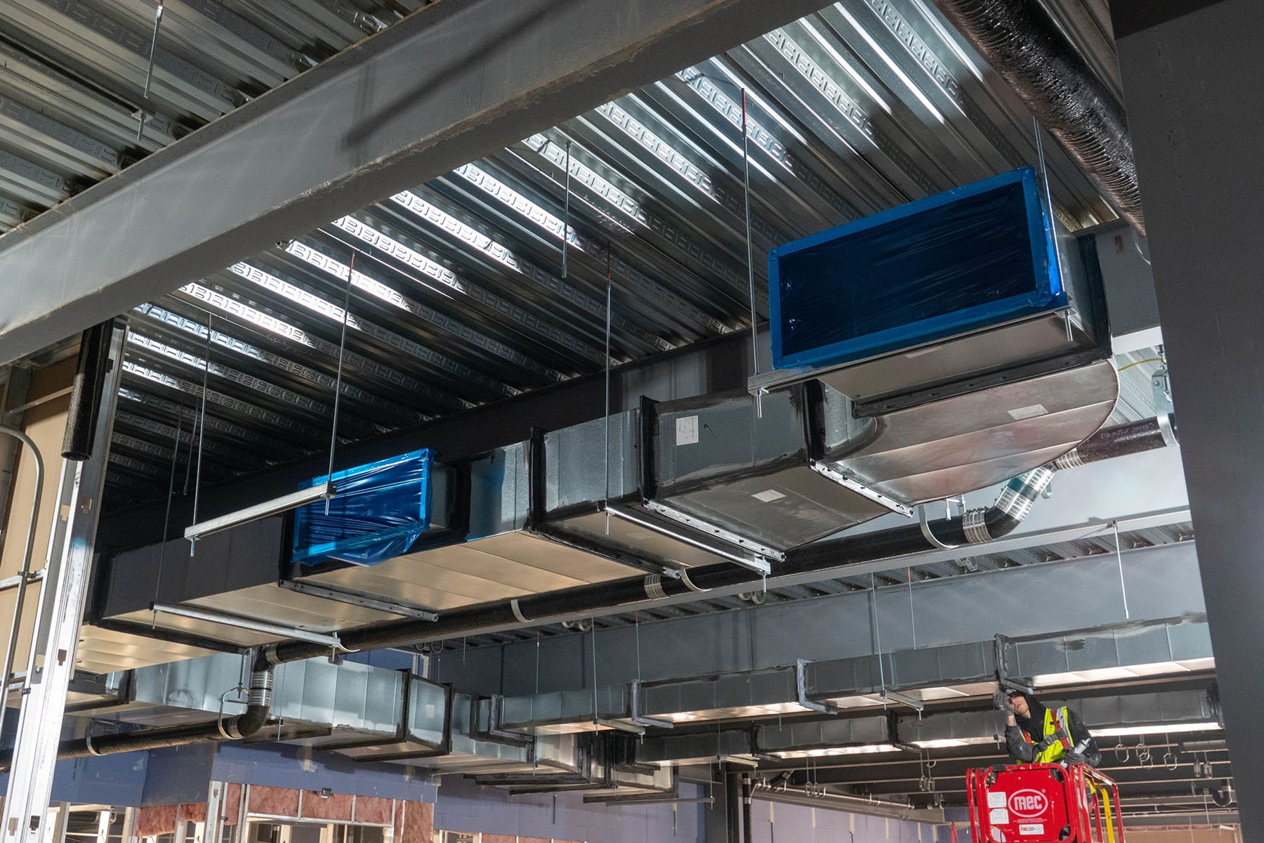 Photo of vents installed in the lab expansion building with worker in background.