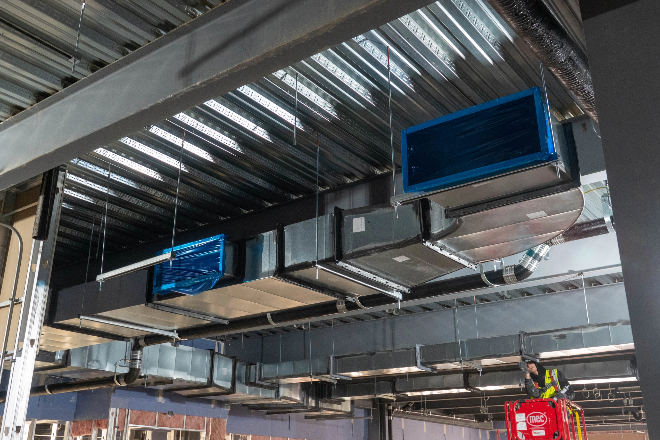 Photo of vents installed in the lab expansion building with worker in background.