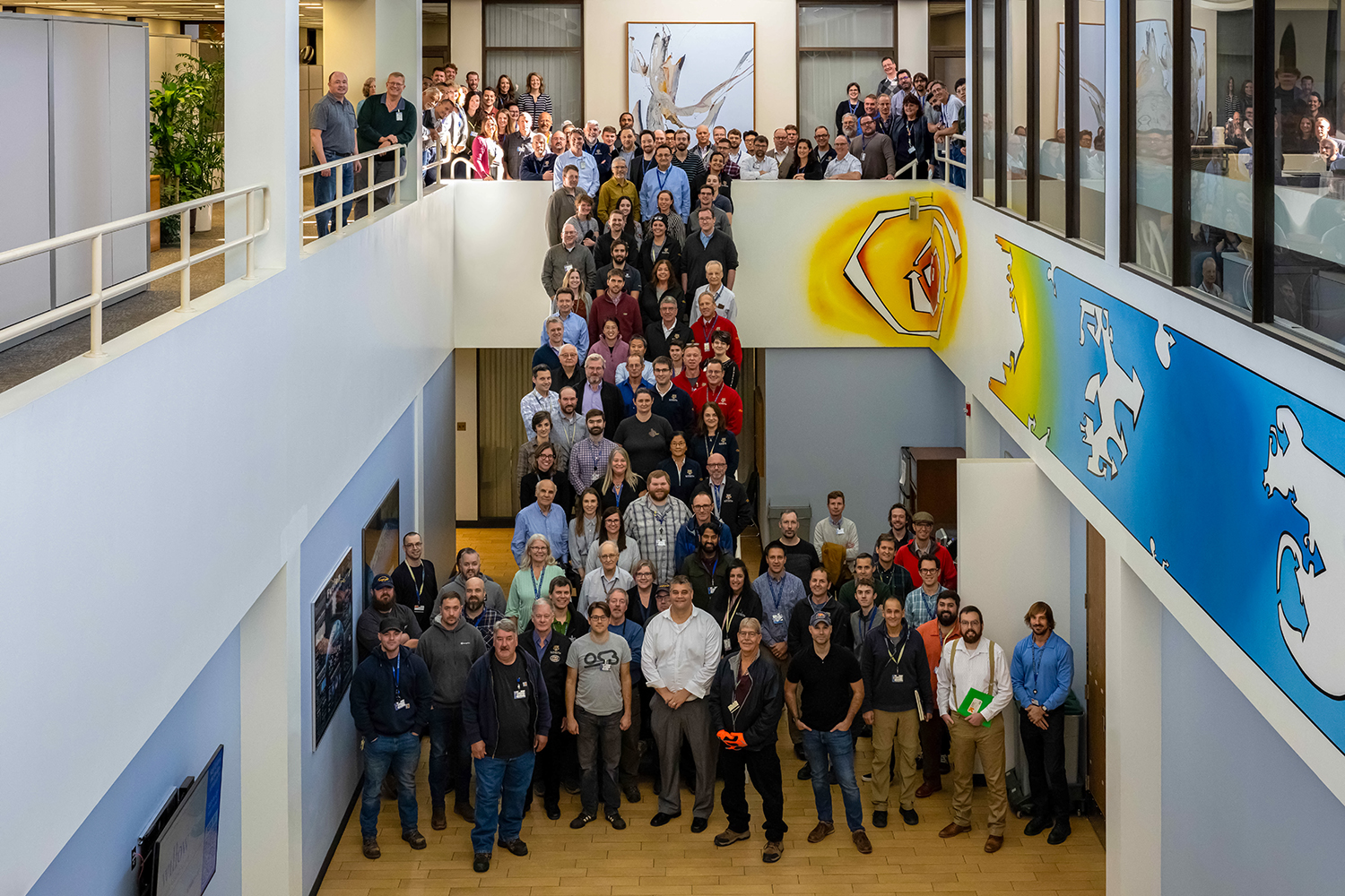 Group photo of LLE employees standing in lobby and stairs.