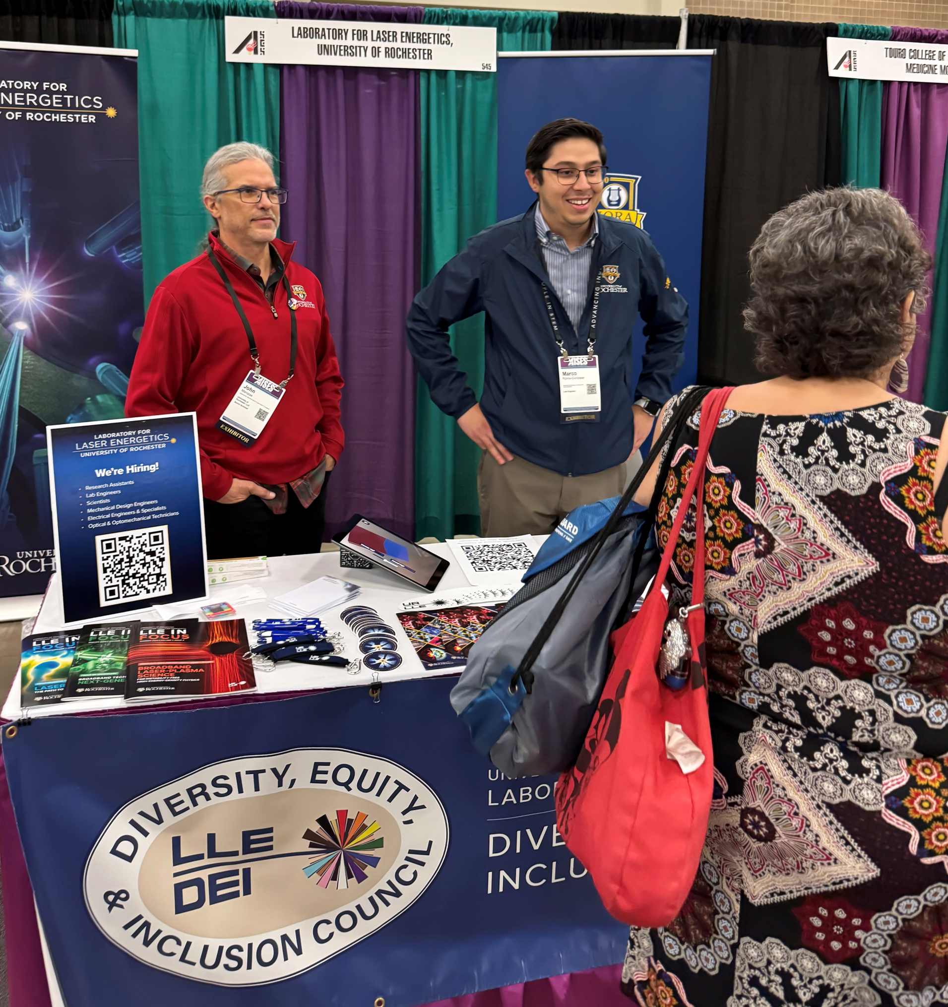 Two members from LLE's DEI council standing at a booth promoting LLE at a recruiting event.