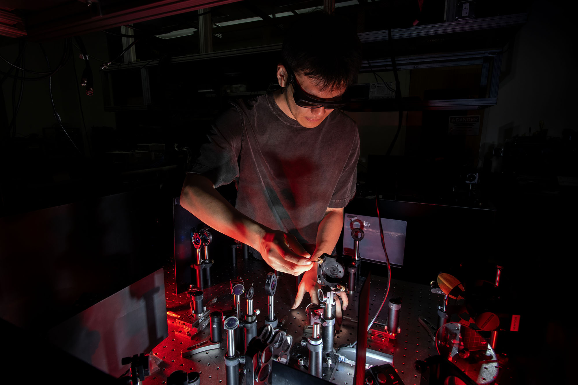 A student working in a laboratory under dark red lighting.