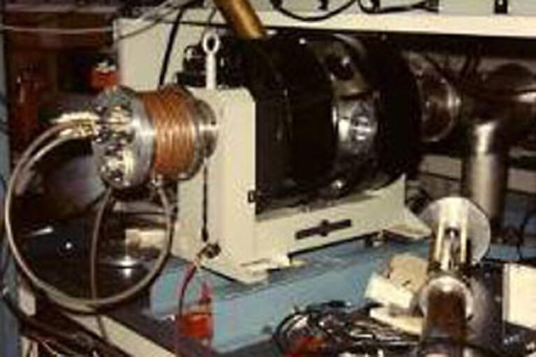 Close-up of a mechanical assembly with a rotating coil or motor component mounted to a metal base with attached cables.