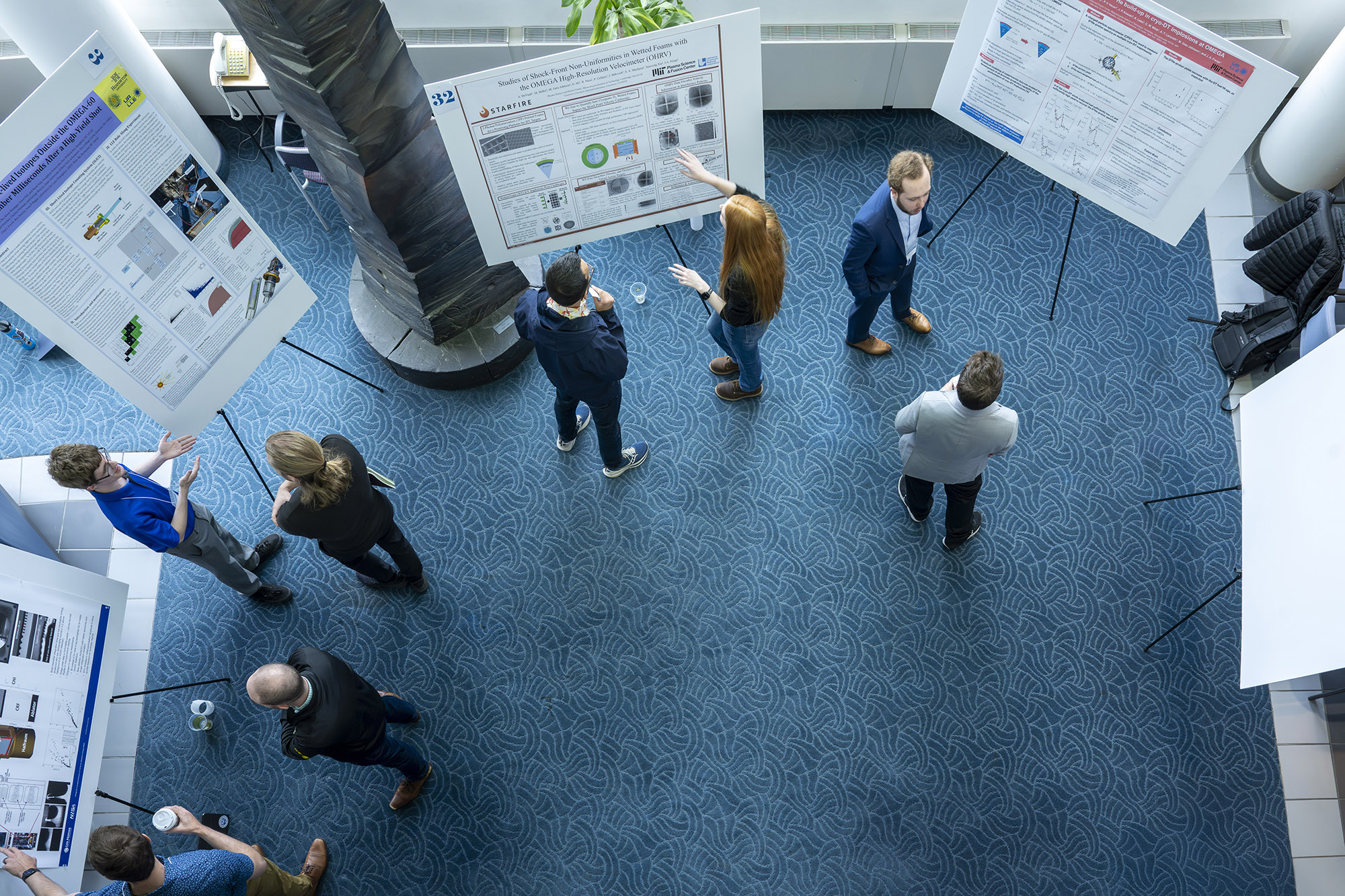 Conference attendees gathered around scientific posters viewed from above.