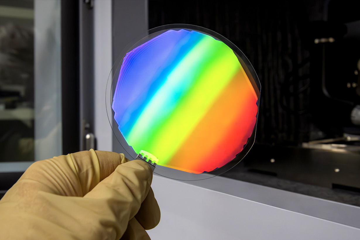 Gloved hand holding colorful circular optic.