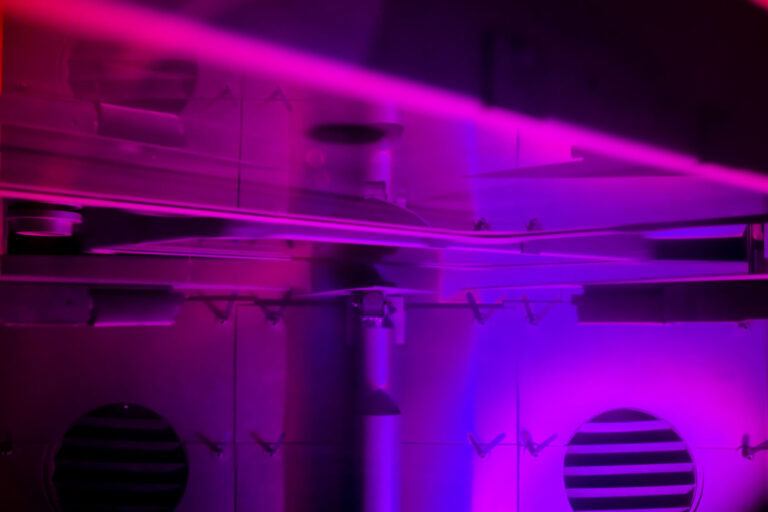 Photo of optical equipment bathed in purple/pink light.