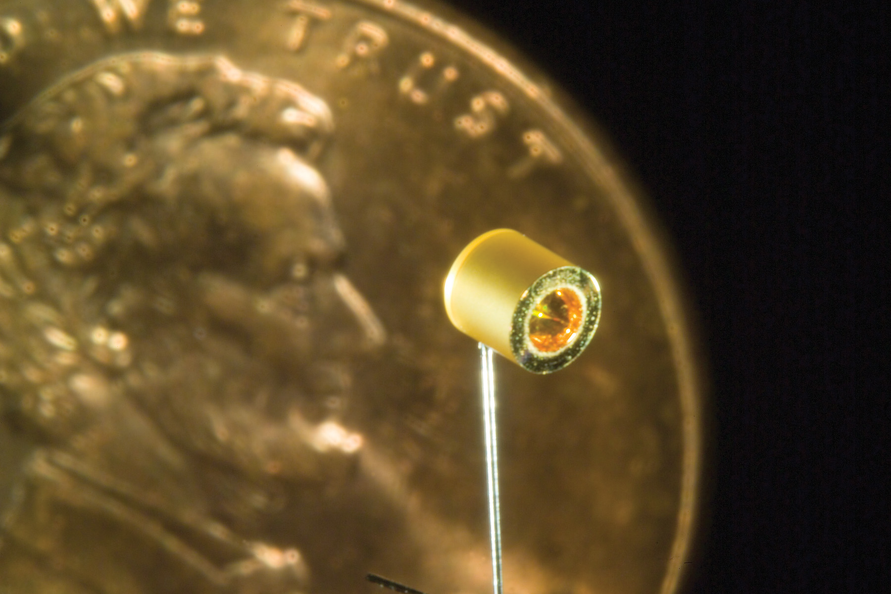 Small cylindrical target mounted on a thin rod shown next to a US penny for scale.