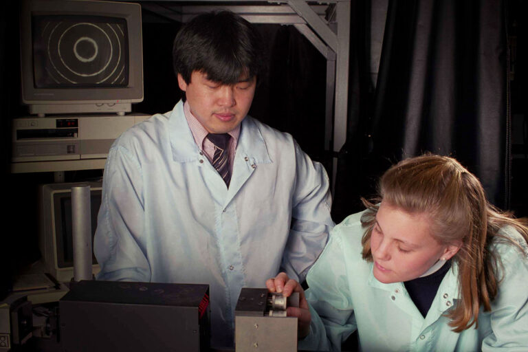 Two scientists in lab coats in a lab examining a liquid crystal apodizer.