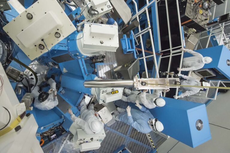 Complex scientific apparatus with mechanical arms, cameras, and diagnostic instruments arranged around a target area in a fusion experiment setup.