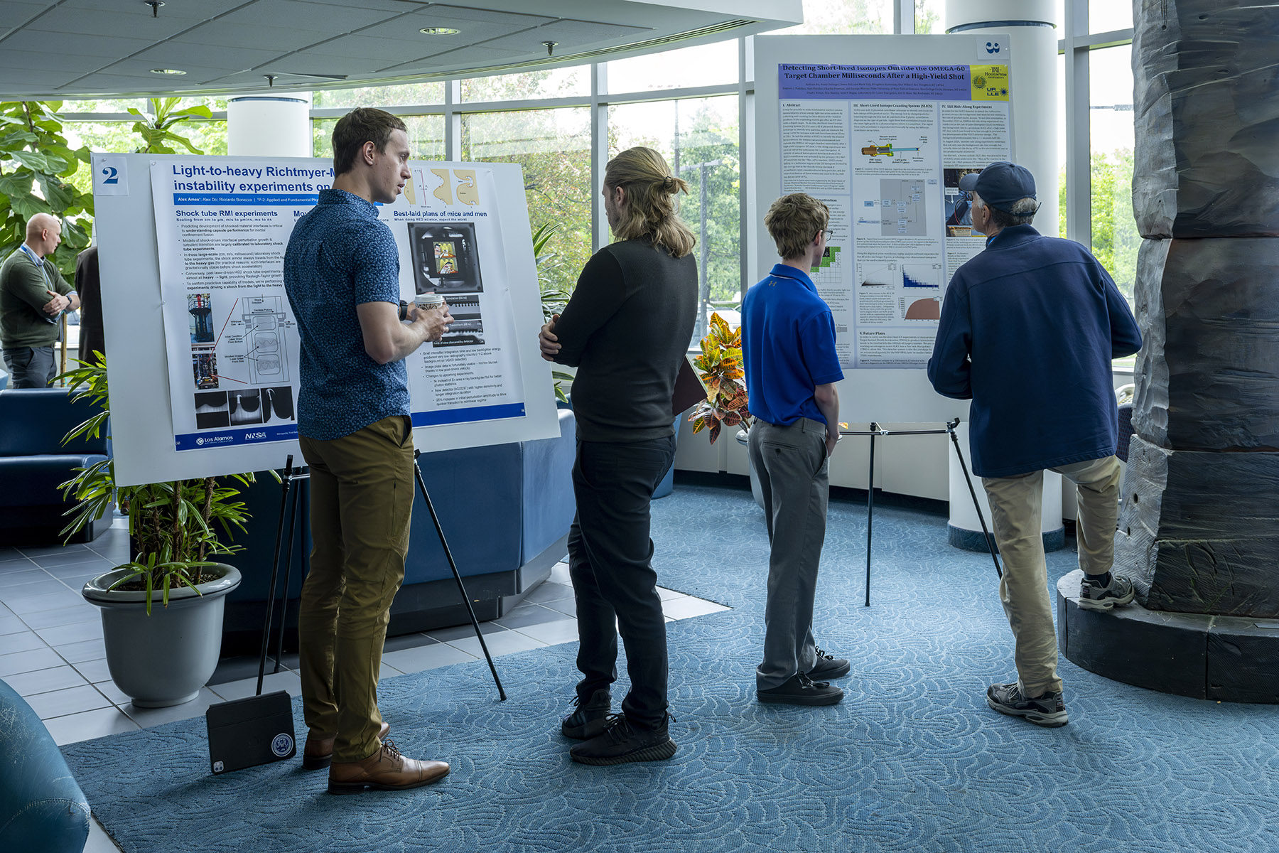 Students and researchers gathered around scientific posters on display on easels.