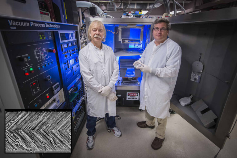 Two researchers wearing lab coats stand in a laser laboratory surrounded by high-tech optical equipment and control systems.