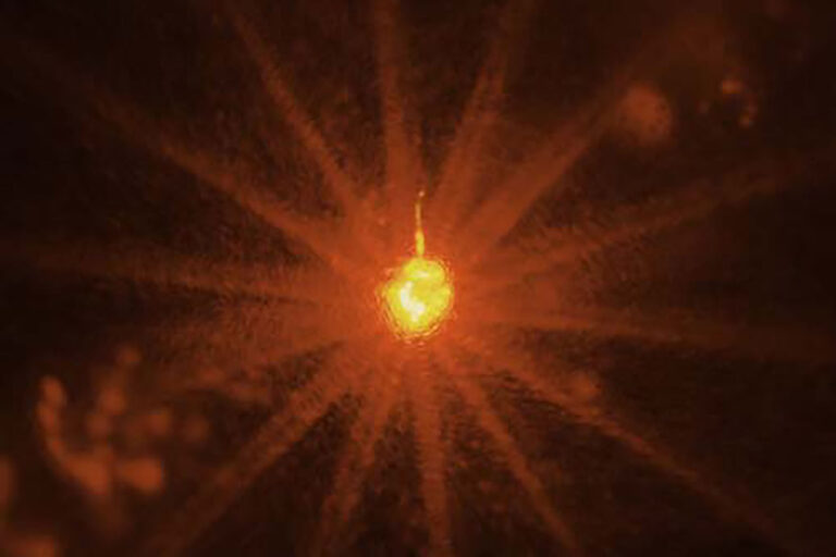 Image of an OMEGA 60 target shot, featuring a vivid yellow light at the center surrounded by multiple red beams radiating outward.