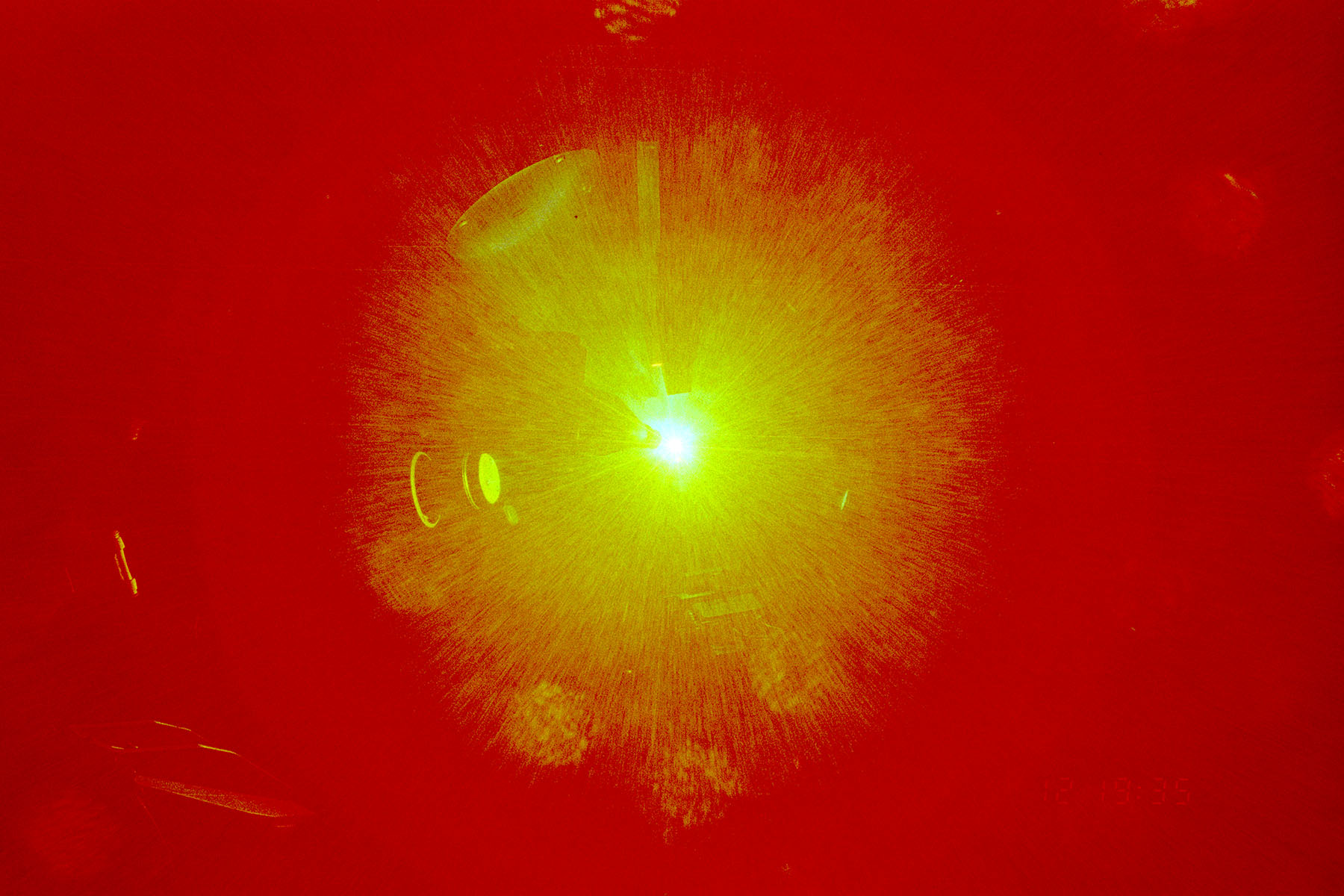 A bright green laser beam illuminating a red plasma-like burst, captured during a high-energy laser experiment.