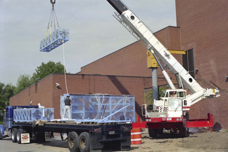 OMEGA Laser construction and installation taken from outside the building. A crane is shown lifting large laser system components.