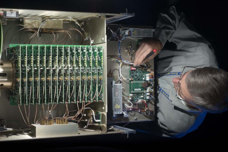 Photograph taken from above of an engineer adjusting computer circuit boards.