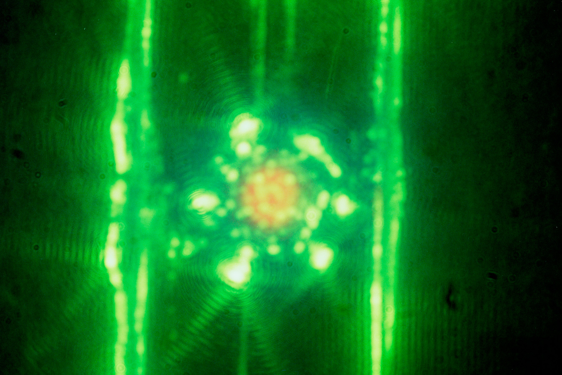 A photo of a laser experiment within the target chamber showing remnants of spider webs, in green, on either side of the target, in orange .