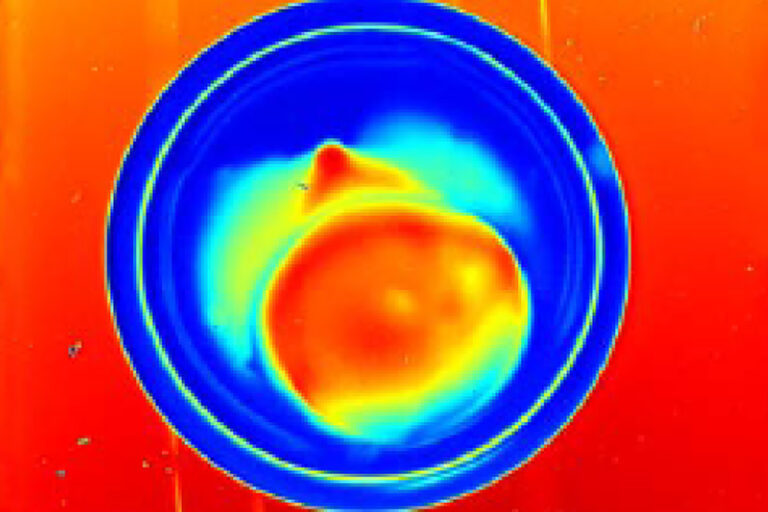 Colorful cross-section visualization of a spherical target showing asymmetry in bright red, yellow, and blue regions.