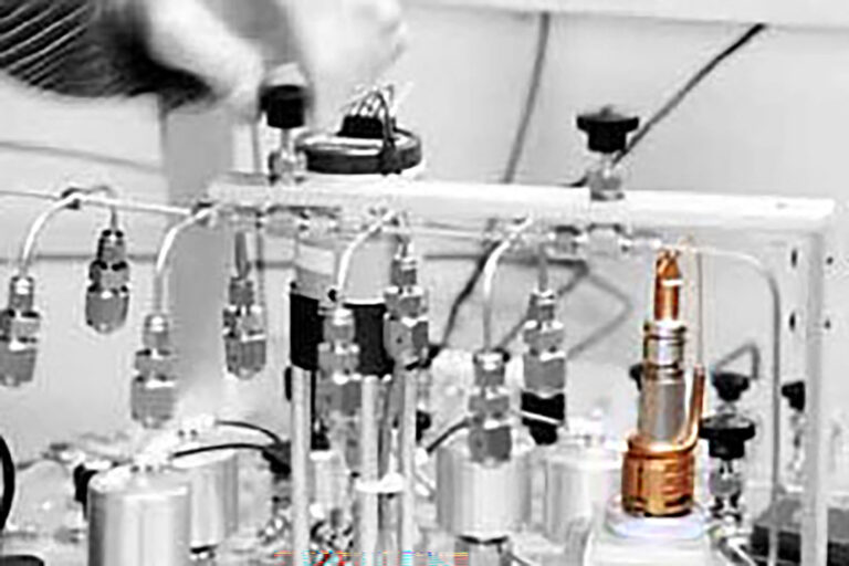 A photo of lab equipment with a person's hand making an adjustment.