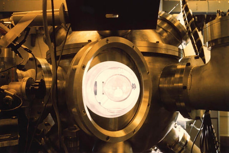 Interior of a vacuum chamber showing a circular target mount and diagnostic hardware illuminated by warm light.