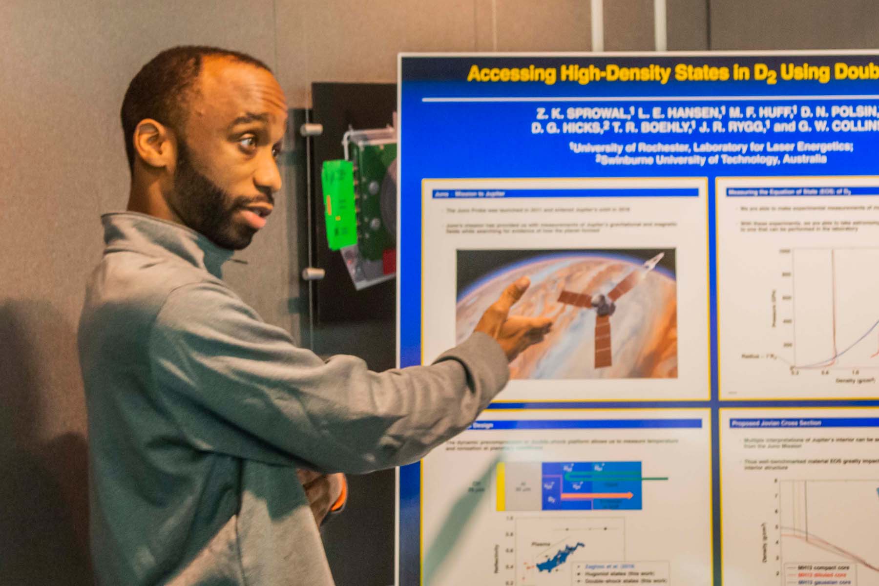 Zaire Sprowal gesturing toward a scientific poster.