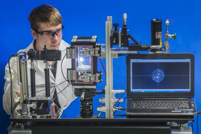 Person in lab attire working with lab equipment.