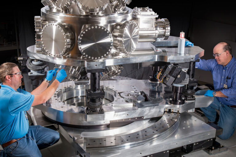 Two people working on machine equipment.