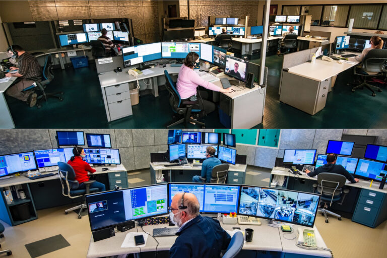 Control room with multiple operators seated at computer stations monitoring dozens of screens showing live experimental data.