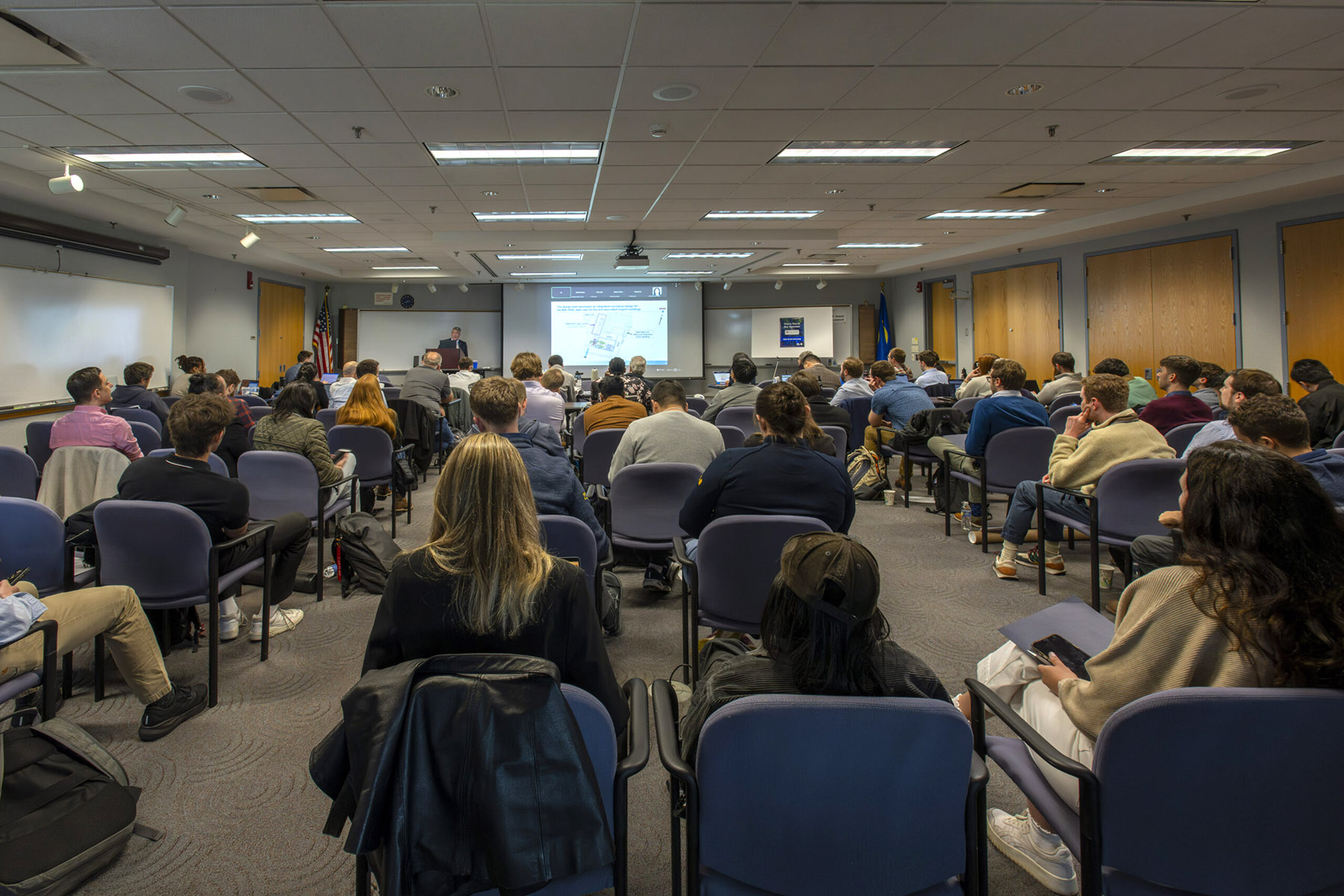 A room full of seated individuals attending a presentation.