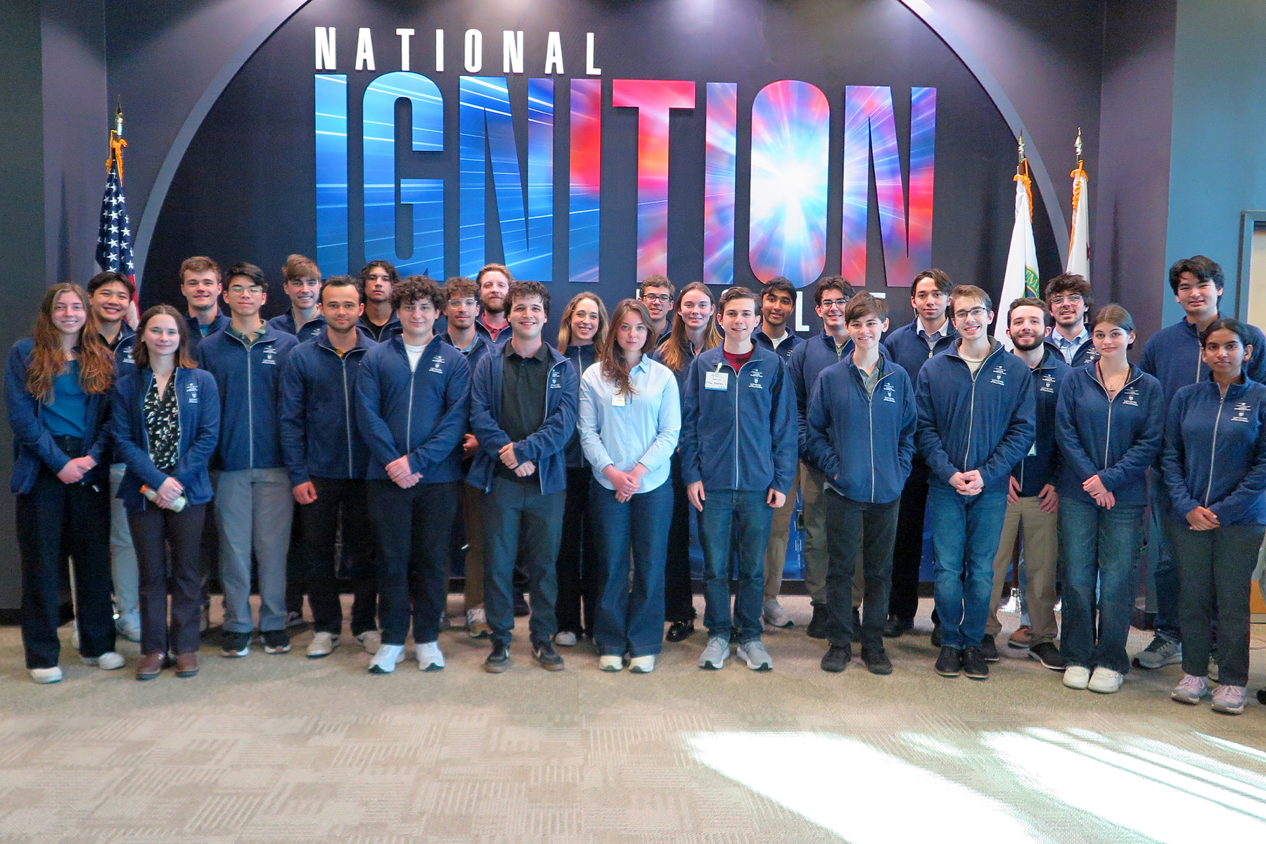 Group photo of students in front of the National Ignition Facility wall sign.