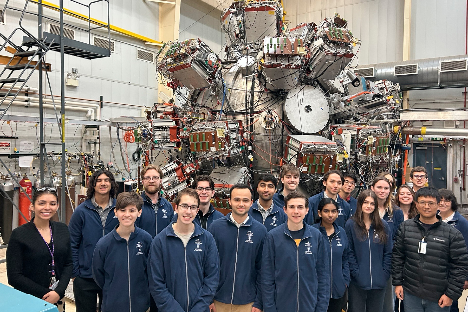 Photo of students infront of a complex machine at Los Alamos National Laboratory.