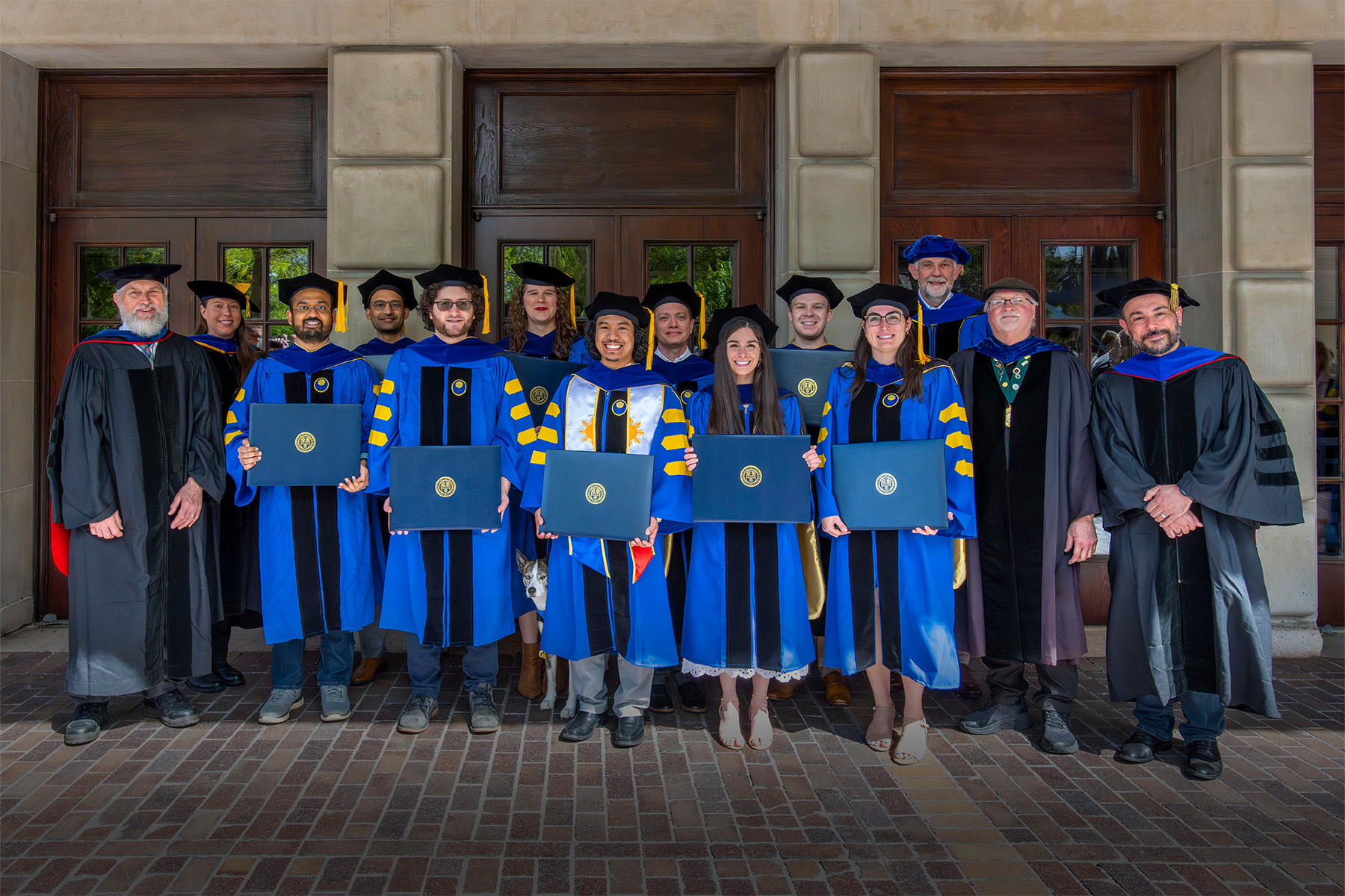 Group of graduate students and mentors standing outside Eastman School of Music's Kodak Hall.