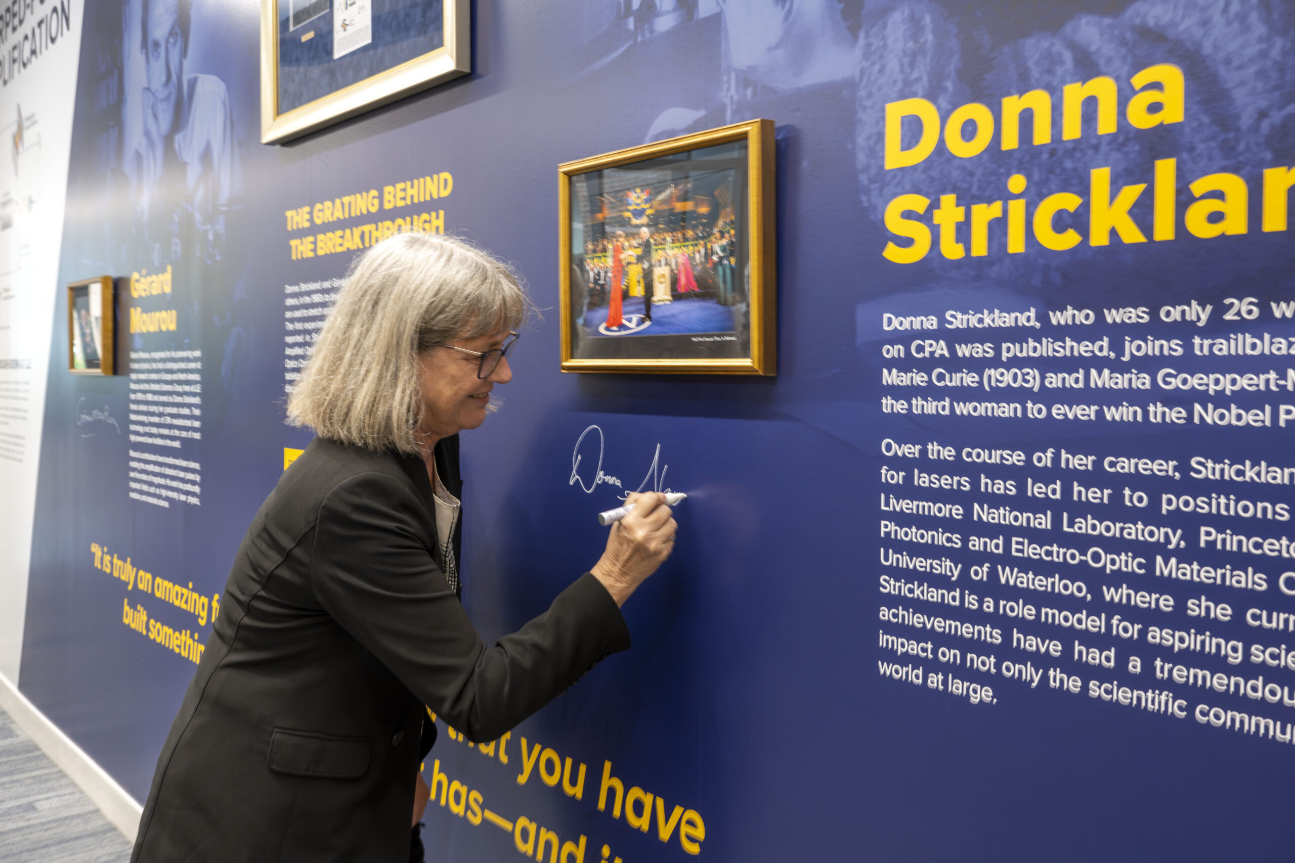 Donna Strickland signing Nobel Prize Winning Research mural in the LLE's Atrium.