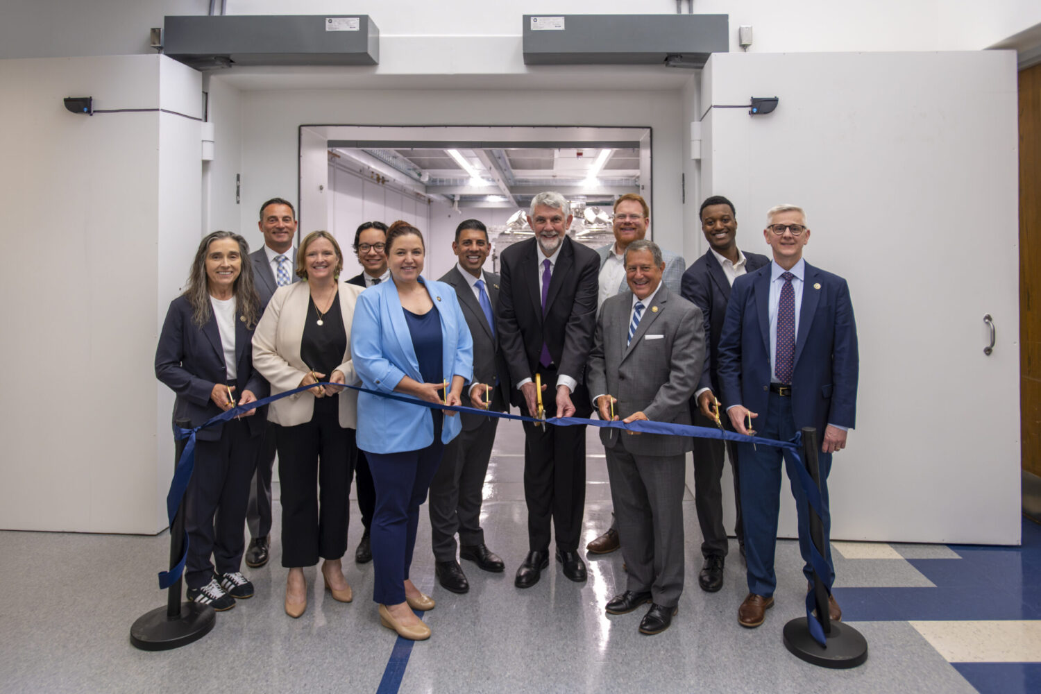 Photo of officials cutting a ribbon in front of the MTW-OPAL Target Chamber.