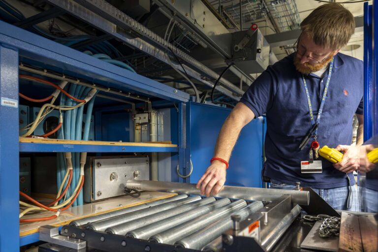 Heath Ferry installing a new capacitor with a custom blue colored lift in the OMEGA Laser System.